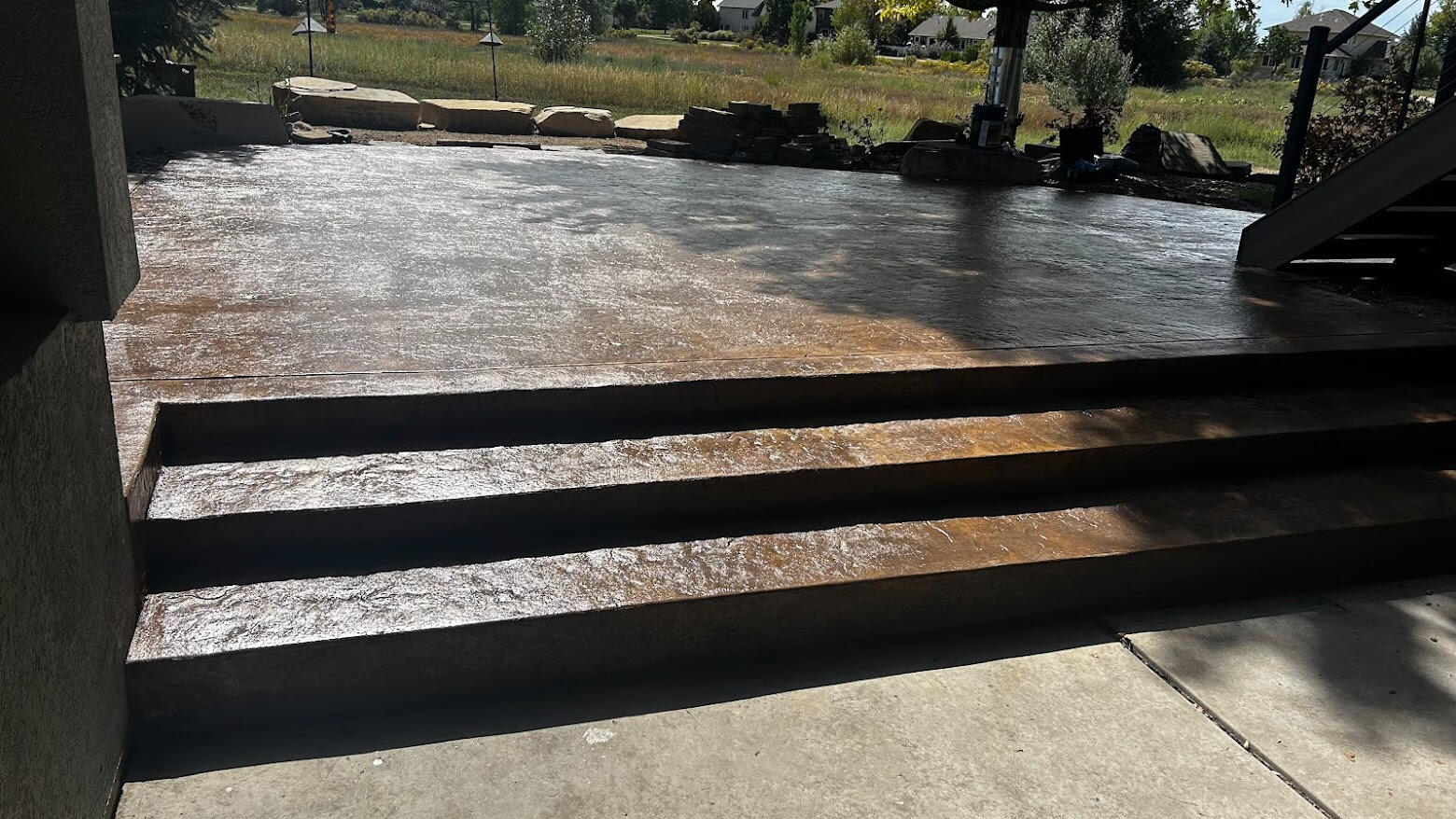 Stamped concrete patio with steps in Fort Collins, Colorado featuring a dark decorative finish for a modern outdoor living space