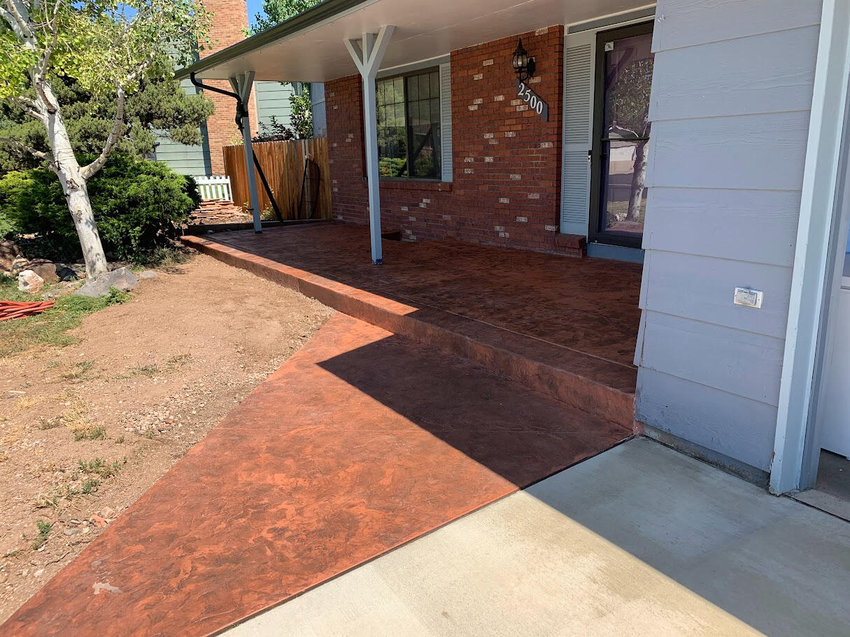 Stamped concrete front porch in Fort Collins, CO with a rich reddish-brown finish and custom texture by a local concrete contractor